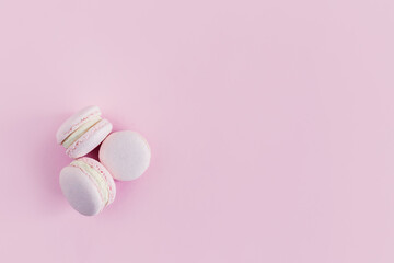 Tasty french macarons on a pink pastel background.