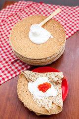 Pancake with red caviar and sour cream during Shrovetide