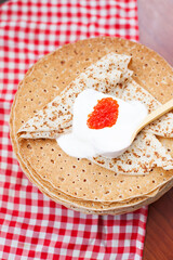 Shrovetide, pancakes with sour cream on wooden background. The view from the top.