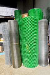 Array of metal and green plastic rolls of wire mesh used in the construction industry for sale at a hardware store in the Philippines, Asia