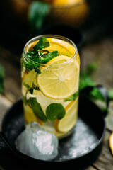 Lemonade with ice and mint in a glass glass on a wooden table