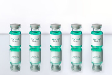 Development and creation of a coronavirus vaccine COVID-19. Five ampoules on white reflective surface. Healthcare and medical concept.
