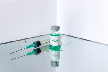 Development and creation of a coronavirus vaccine COVID-19. Ampoule and syringe. Spilled liquid on white reflective surface. Healthcare and medical concept.