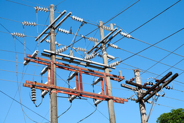 Detail close-up view of a confusing mix of electrical cables attached to electrical posts, against a blue sky, Philippines, Asia