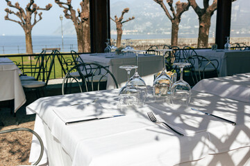Empty restaurant terrace with glasses on the white tablecloth. Closed bar concept during lockdown