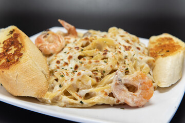 Mexican culinary favorite seafood pasta garnished with garlic bread on a plate.