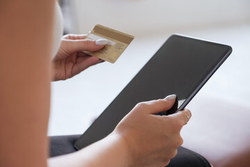 Brunette Caucasian woman in white blouse and dark skirt making an order via internet and pay using credit card. Online shopping concept. Space for text
