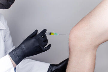 An orthopedic surgeon gives an injection in the knee. Treatment of osteoarthritis with hormonal...