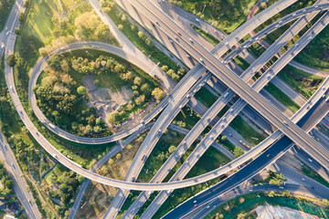 Aerial view of road interchange or highway intersection with busy urban traffic speeding on the...
