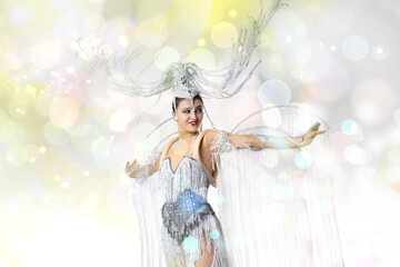 Beautiful young woman in carnival, stylish masquerade costume with feathers dancing on white studio background with shining neoned bokeh. Concept of celebration, festive time, party. Copyspace