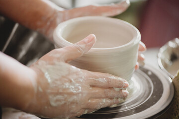 Close up of potter's hands creating an earthen jar.