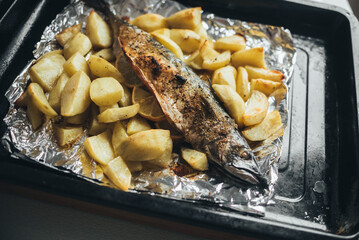 Homemade food, fish mackerel baked with potatoes in foil