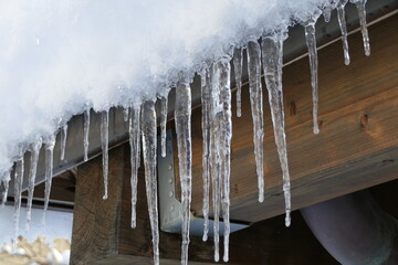 Outside in winter long icicles hanging from the roof rafters