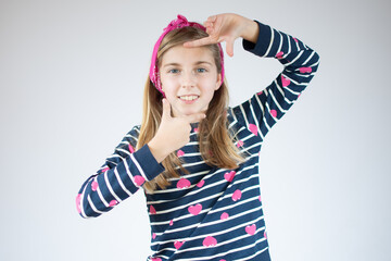 Little girl making a frame shape with hands over white background.