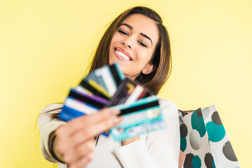 Beautiful happy girl with credit card and shopping bags isolated on yellow background with copyspace Online Shopping concept