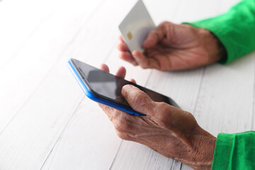elderly women hand holding credit card and using smart phone shopping online 