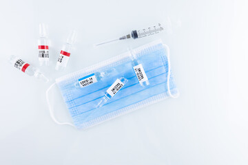 Vials of COVID-19 vaccines are placed on a medical mask, and next to it is a bottle of coronavirus