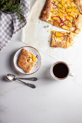 Summer galette with peach with coffe on marble background, top view, copy space. Summer food, summer pie on parchment paper 