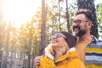 portrait of couple of two happy people looking at the trees in the forest and enjoying together the...