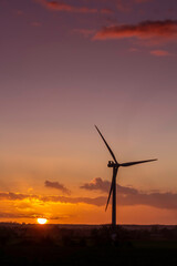 Obraz premium wind turbine silhouetted against a beautiful sunset.