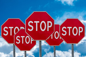 Stop Signs Against Cloudy Blue Sky