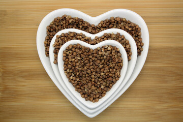 Buckwheat in a heart-shaped bowl on a wooden background.