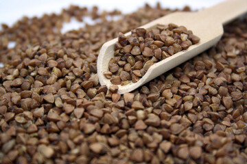 Buckwheat in a wooden spoon on a wooden background.