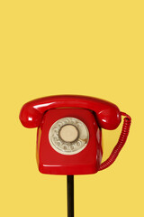 red rotary dial telephone on a black stand