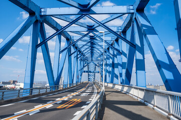 青い橋の内側から見た、頑丈な鉄のトラスと伸びるていく道路の風景