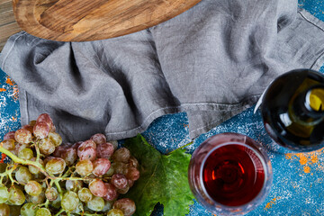 Bunch of grapes, a glass of red wine and a bottle of wine on blue background, close up