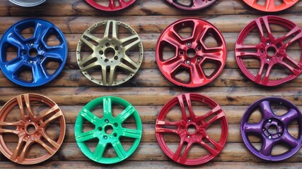 
Old multicolored car rims nailed to a log wooden shield