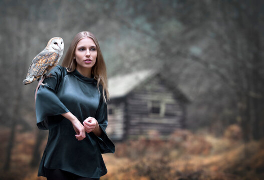 Misterioius young blond girl with a barn owl white bird in a foggy forest