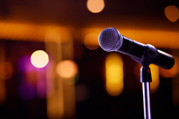 Fototapeta na wymiar Close up of microphone on stage lighting at concert hall or conference room. copy space banner. soft focus.