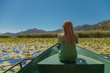 Happy carefree woman in travels by boat.
Traveller woman enjoying open spaces on lake, serenity in nature.  The concept of outdoor activities and tourism in nature. Skadar lake in Montenegro.
