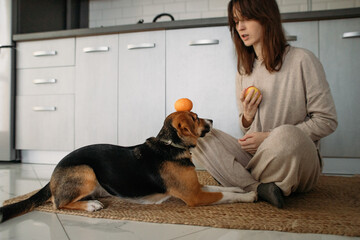young woman spends time with a dog in a cozy kitchen