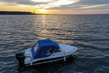 White pleasure boat against the setting sun on the Gulf of Finland on a summer day. Powerboat. Evening. Reflection of sun glare in the water.