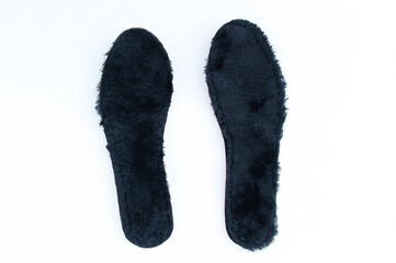 Black fur insoles for winter shoes on white background.