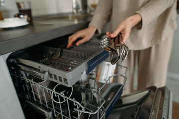 woman unloads dishes from the dishwasher