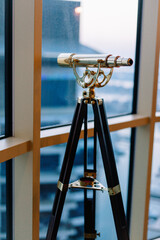 Beautiful retro telescope in room with big windows. 