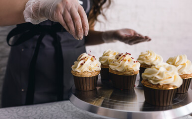the chef girl sprinkles icing on fresh cupcakes covered in vanilla cream.Sweet homemade cupcakes...