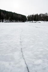 Fototapeta na wymiar Fracture on the ice on the surface of a frozen lake or river, vertical 