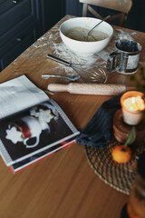 White bowl with dough and spoon in it, on the wooden table in the kitchen. The process of mixing ingredients for pastry. Closeup, selective focus.