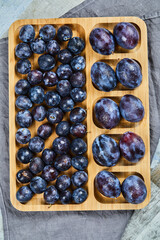 Garden plums on wooden platter with gray tablecloth