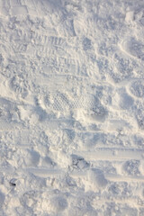 Detail of a snow surface with a lot of structure. Snow structure in winter. Snowy structure pattern with footprints, tire tracks and sled tracks.