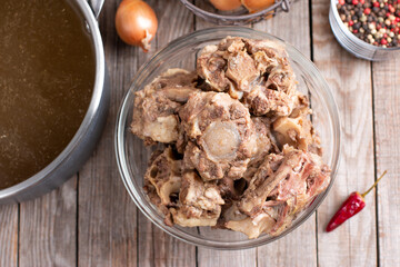 Beef bones to make homemade bone broth for a healthy diet. Saucepan with bone broth on the table. Top view