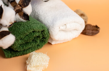 green and white, terry towel on a beige background, with a branch of cotton, close-up. Spa
