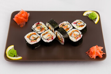 Complex roll - hot and cold with salmon, flying fish roe and avocado on white plate on black background