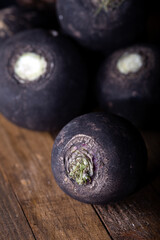 Fresh raw black radishes on wooden background.