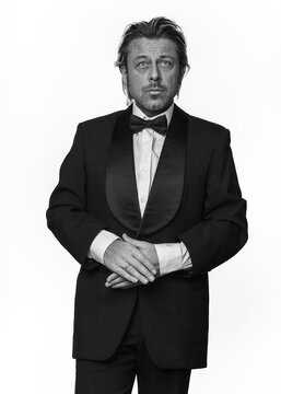 Man in tuxedo in front of white background. Black and white photo.