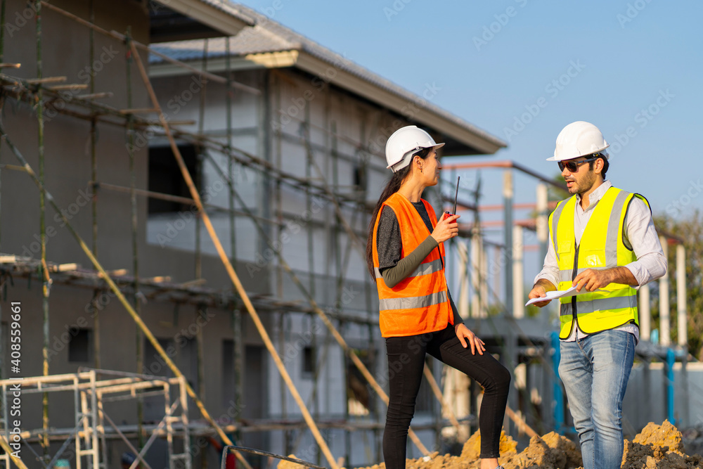 Wall mural beautiful female engineer with a male foreman wearing a protective helmet, talk together about worki